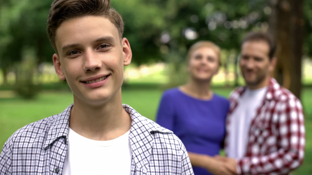 Teenage boy with blurred couple in background